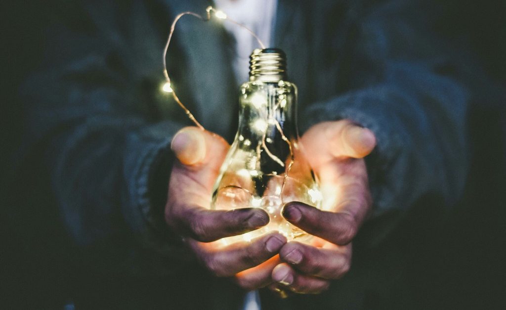 mani che tengono una lampadina